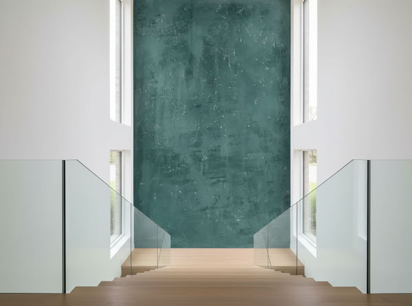 Moderner Innenraum mit einer Treppe, die von Glasgeländern flankiert wird, und einer großen Wand mit W 137 Classic hohe Wand im Treppenhaus