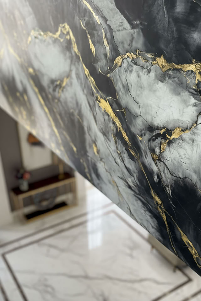 Wand mit W Classic Marmoroptik in Schwarz, Weiß und Gold, daneben ein Raum mit hellem Marmorboden und großen Fenstern.