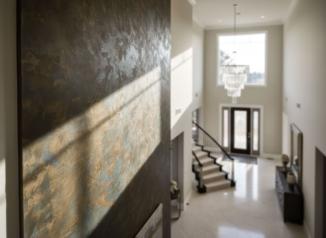 Großer, heller Eingangsbereich eines Hauses mit Treppe, grosse Rostwan, Kronleuchter und Doppeltüren.